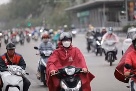 Do thời tiết có gió lạnh kèm mưa phùn, nên nhiều người mặc áo mưa. (Ảnh: Thanh Tùng/TTXVN)