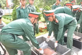 Nghi thức hạ quan hài cốt các liệt sỹ. (Ảnh: Nguyên Dung/TTXVN)