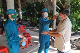 Đo thân nhiệt và hướng dẫn khai báo y tế khi qua các chốt kiểm soát dịch trên tuyến đường bộ. (Ảnh: TTXVN)