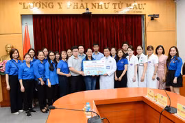 Đoàn thanh niên TTXVN trao bảng tượng trưng 70 suất quà và hơn 300 đầu sách cho Khoa Nhi - Bệnh viện K (cơ sở 3). (Ảnh: Minh Đức/TTXVN) 