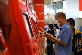 Hành khách làm thủ tục trực tuyến tại kios của Vietjet tại sân bay Nội Bài. (Ảnh: Huy Hùng/TTXVN)