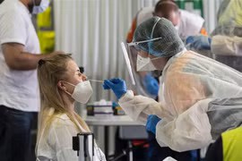 Nhân viên y tế lấy mẫu xét nghiệm COVID-19 cho người dân tại London (Ảnh: AFP/TTXVN)