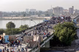 Người biểu tình phản đối chính phủ Iraq tràn vào cây cầu al-Sinek để tiến vào vùng Xanh ở thủ đô Baghdad ngày 17/11/2019. (Ảnh: AFP/TTXVN)