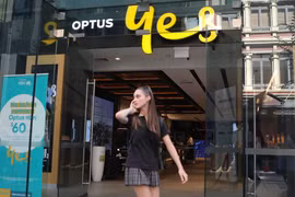 Một phụ nữ sử dụng điện thoại di động khi đi ngang qua cửa hàng Optus ở Sydney, Australia. (Nguồn: Reuters)