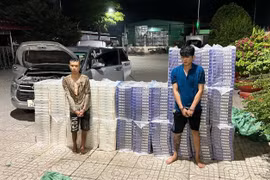 Hai đối tượng vận chuyển 15.000 bao thuốc lá ngoại nhập lậu bị bắt giữ cùng tang vật. (Ảnh: TTXVN phát)