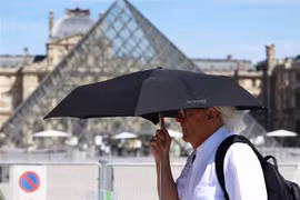 Người dân che ô bảo vệ trong thời tiết nắng nóng tại Paris, Pháp. (Ảnh: THX/TTXVN)