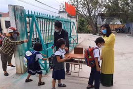 Học sinh được kiểm tra thân nhiệt, rửa tay sát khuẩn trước khi vào lớp. (Ảnh: Công Thử/TTXVN)