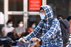 Người dân sử dụng quần áo chống nóng khi phải di chuyển ngoài trời. (Ảnh: Hoàng Hiếu/TTXVN)