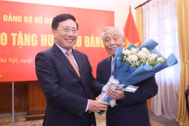 Phó Thủ tướng Thường trực Phạm Bình Minh tặng hoa, chúc mừng Nguyên Phó Thủ tướng Nguyễn Mạnh Cầm nhận Huy hiệu 75 năm tuổi Đảng. (Ảnh: Lâm Khánh/TTXVN)