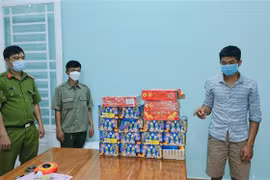 Đối tượng Phạm Nhật Hồng Đăng (bên phải) cùng số tang vật thu giữ 18 hộp pháo nổ, trọng lượng 26kg. (Ảnh: TTXVN phát)