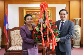 Bà Sounthone Sayachac trao hoa chúc mừng Quốc khánh cho Đại sứ Nguyễn Bá Hùng. (Ảnh: Phạm Kiên/Vietnam+)