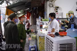 Lực lượng chức năng nhắc nhở các cửa hàng, quán ăn thực hiện đúng các biện pháp phòng, chống dịch bệnh COVID-19. (Ảnh: TTXVN)