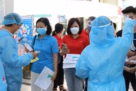 Kiểm tra khai báo y tế, thân nhiệt cho người lao động Dầu khí trước khi bước vào khu vực tiêm chủng. (Ảnh: PV/Vietnam+)