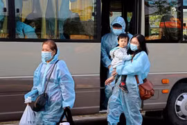 Công dân về từ Pháp xuống xe vào khu cách ly tập trung. (Ảnh: Thanh Hải/TTXVN)