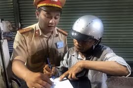 Lái xe môtô vi phạm nồng độ cồn ký biên bản vi phạm hành chính. (Ảnh: Nguyên Linh/TTXVN)