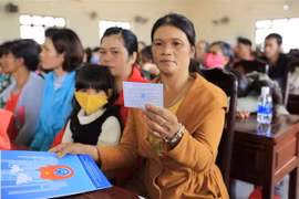 Người dân cầm trên tay thẻ bảo hiểm y tế sau khi được hướng dẫn sử dụng. (Ảnh Đặng Tuân/TTXVN)