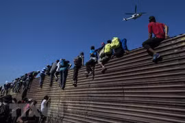 Người di cư vượt qua bức tường biên giới Mỹ-Mexico ở gần cửa khẩu El Chaparral, Tijuana, bang Baja California, Mexico ngày 25/11/2018. (Nguồn: AFP/TTXVN)
