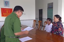 Đối tượng Cao Thị Ánh nghe tống đạt quyết định khởi tố. (Ảnh: Thế Anh/TTXVN)