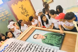 Các em học sinh hào hứng tham quan quyển sách thư pháp viết về Đại tướng Võ Nguyên Giáp. (Ảnh: Võ Dung/TTXVN)