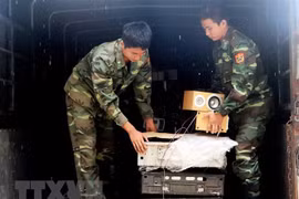 Kiểm đếm và vận chuyển tang vật buôn lậu hàng hóa vào kho tạm giữ. (Ảnh: Công Mạo/TTXVN)