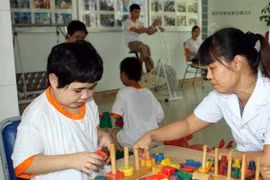 Nhân viên y tế giúp các em là nạn nhân chất độc da cam nhận biết màu sắc, hình dáng đồ vật qua trò chơi xếp hình. (Ảnh minh họa. Nguồn: TTXVN)