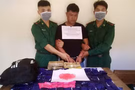 Đối tượng vận chuyển ma túy (ở giữa) cùng tang vật. (Ảnh: TTXVN)