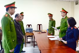 Lực lượng chức năng đọc lệnh khởi tố và bắt tạm giam Trần Quang Anh. (Ảnh: TTXVN phát)
