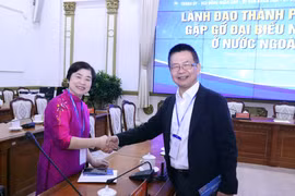Cái bắt tay nhất trí góp sức phụng sự quê hương giữa bà Trần Tuệ Tri, kiều bào Singapore (bên trái) và ông Lâm Việt Tùng, kiều bào tại Hà Lan. (Ảnh: Xuân Khu/TTXVN)