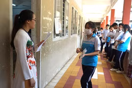 Cán bộ coi thi kiểm tra thông tin thí sinh trước khi vào phòng thi tại điểm thi Trường THPT Thủ Đức. (Ảnh: Thu Hoài/TTXVN) 
