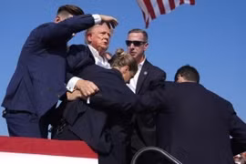 Mật vụ Mỹ bảo vệ cựu Tổng thống Donald Trump rời khỏi bục diễn thuyết trong cuộc vận động tranh cử ở Butler, bang Pennsylvania. (Ảnh: THX/TTXVN)
