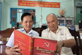 Ông Lê Văn Thiệm (bên trái) tại ấp 6, thị trấn Giồng Trôm (Bến Tre), Đảng viên 35 năm tuổi đảng trao đổi nghiên cứu văn kiện của Đảng với đảng viên trong chi bộ. (Ảnh: Huỳnh Phúc Hậu/TTXVN)