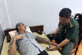 Cán bộ Quân y Đồn Biên phòng Cửa khẩu Cảng Gianh thăm khám sức khỏe ban đầu cho thuyền viên bị nạn Nguyễn Văn Bình. (Ảnh: TTXVN phát)