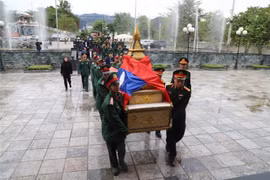 Đại diện chính quyền của hai nước và cộng đồng người Việt đang làm ăn sinh sống tại Oudomxay tập trung dọc tuyến đường đoàn xe đi qua để tiễn đưa các liệt sỹ lên đường về đất Mẹ. (Ảnh: Phạm Kiên/TTXVN)