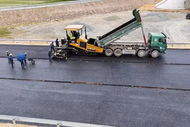Nhà thầu Tổng Công ty Vinaconex thi công thảm bêtông nhựa mặt đường tại nút giao quốc lộ 8A, xã Thanh Bình Thịnh, huyện Đức Thọ. (Ảnh: Hữu Quyết/TTXVN)