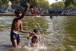 Trẻ em giải nhiệt tránh nóng tại một ao nước ở New Delhi của Ấn Độ ngày 7/6. (Ảnh: THX/TTXVN)