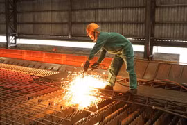 Công nhân Nhà máy cán thép Thái Trung, Công ty Cổ phần gang thép Thái Nguyên lấy mẫu thép cán mới ra lò. (Ảnh: Hoàng Nguyên/TTXVN) 