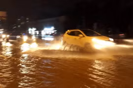 Các phương tiện di chuyển trên mặt đường Phạm Văn Đồng, quận Cầu Giấy bị ngập nước tối 15/7. (Ảnh: Văn Điệp/TTXVN)