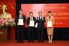 Ông Hoàng Bình Quân, Ủy viên Trung ương Đảng, Trưởng Ban Đối ngoại Trung ương trao tặng Kỷ niệm chương 'Vì sự nghiệp Đối ngoại Đảng' cho Phó Tổng Giám Vũ Việt Trang và hai Trưởng ban Biên tập của TTXVN. (Ảnh: Doãn Tấn/ TTXVN) 