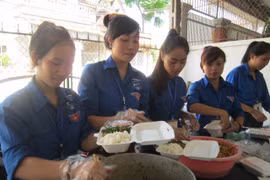 Các sinh viên tình nguyện chuẩn bị suất cơm miễn phí cho thí sinh. (Ảnh: Bích Huệ/TTXVN)