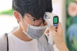 Thí sinh đo thân nhiệt trước khi vào khu vực thi tốt nghiệp trung học phổ thông. (Ảnh: Minh Sơn/Vietnam+)