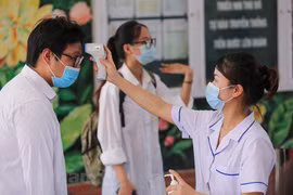 Thí sinh được kiểm tra thân nhiệt trước khi vào điểm thi. (Ảnh: Minh Sơn/Vietnam+)