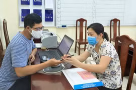 Cán bộ tuyển sinh Trường Tiểu học Nghĩa Dũng (quận Đống Đa, Hà Nội) hỗ trợ phụ huynh làm hồ sơ. (Ảnh: PV/Vietnam+)