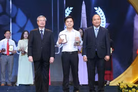 Thủ tướng Nguyễn Xuân Phúc và đồng chí Trần Quốc Vương, Ủy viên Bộ Chính trị, Thường trực Ban Bí thư trao giải A cho tác giả Hùng Võ báo điện tử Vietnamplus, TTXVN. (Ảnh: Doãn Tấn/TTXVN)