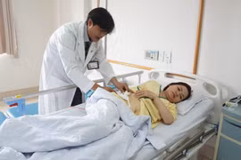 Bà Nguyễn Thị Như T được bác sĩ kiểm tra tình hình sức khỏe trước khi xuất viện. (Ảnh: Lê Xuân/TTXVN)