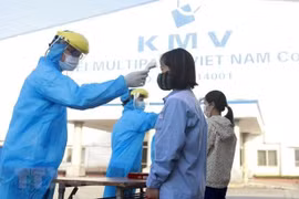 Công nhân được kiểm tra thân nhiệt trước khi vào công ty. (Ảnh minh họa: Hoàng Hùng/TTXVN)