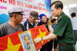 Đại tá Nguyễn Văn Hưng, Chính ủy Bộ đội biên phòng tỉnh Lai Châu tặng cờ Tổ quốc và ảnh Bác Hồ cho người dân biên giới tại bản Tung Qua Lìn, xã Tung Qua Lìn. (Ảnh: TTXVN phát)