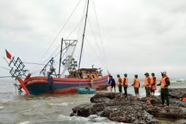 15 cán bộ, chiến sỹ Đồn Biên phòng Cửa Tùng phối hợp với thuyền viên trên tàu di dời tài sản lên bờ và chằng chống, neo giữ để tàu không bị chìm. (Ảnh: TTXVN phát)