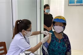 Nhân viên y tế giải thích cho người đến tiêm vaccine COVID-19. (Ảnh: Minh Quyết/TTXVN)