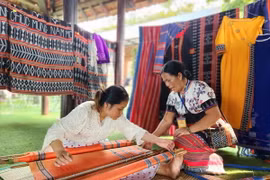 Các nghệ nhân trình diễn kỹ thuật tinh xảo dệt lụa và thổ cẩm truyền thống. (Ảnh: Tường Vi/TTXVN)