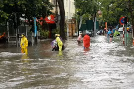 Cảnh sát giao thông Hà Nội giúp dân vượt qua chỗ ngập tại phố Lý Thường Kiệt-Phan Bộ Châu. (Ảnh: Doãn Tấn/TTXVN)